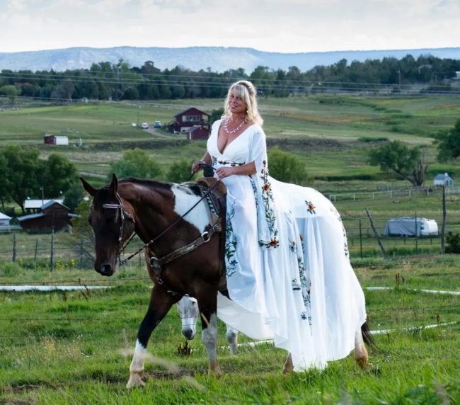 Bride in a white wedding dress riding a horse in the countryside near Three Willows Ranch wedding venue in Colorado