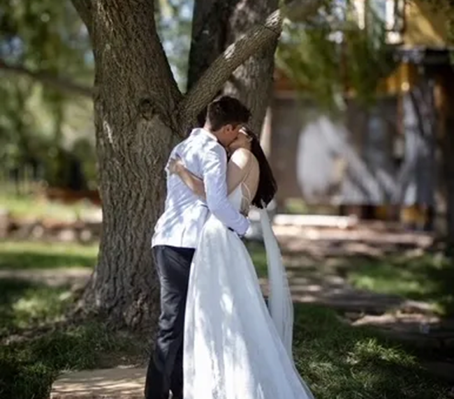 Bride and groom sharing a kiss under a tree during a wedding at Three Willows Ranch Colorado
