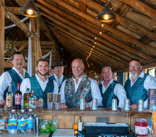 Bartenders serving drinks at the rustic barn bar area during an event at Three Willows Ranch Colorado