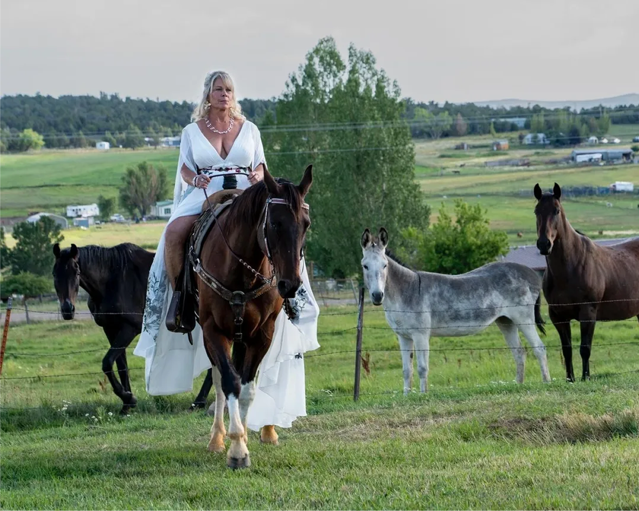 Bride in a white wedding dress riding a horse in the countryside near Three Willows Ranch wedding venue in Colorado