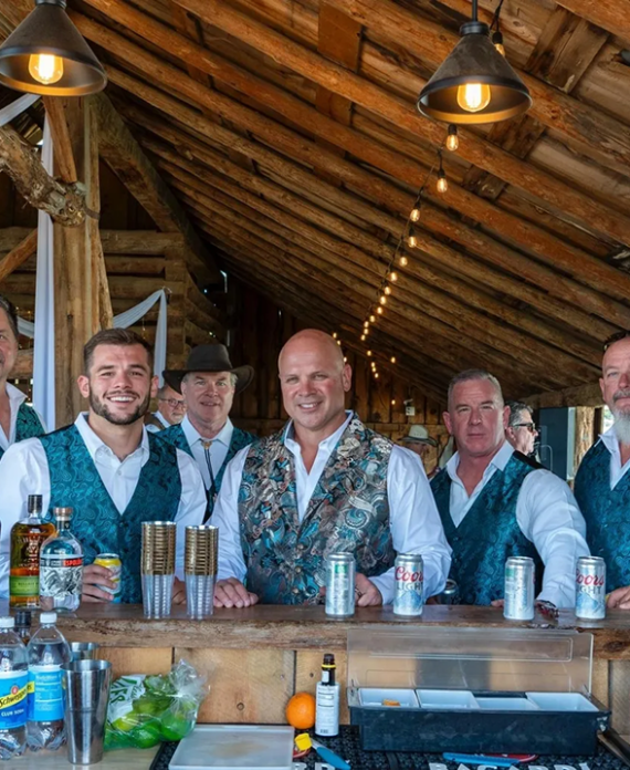 Bartenders serving drinks at the rustic barn bar area during an event at Three Willows Ranch Colorado