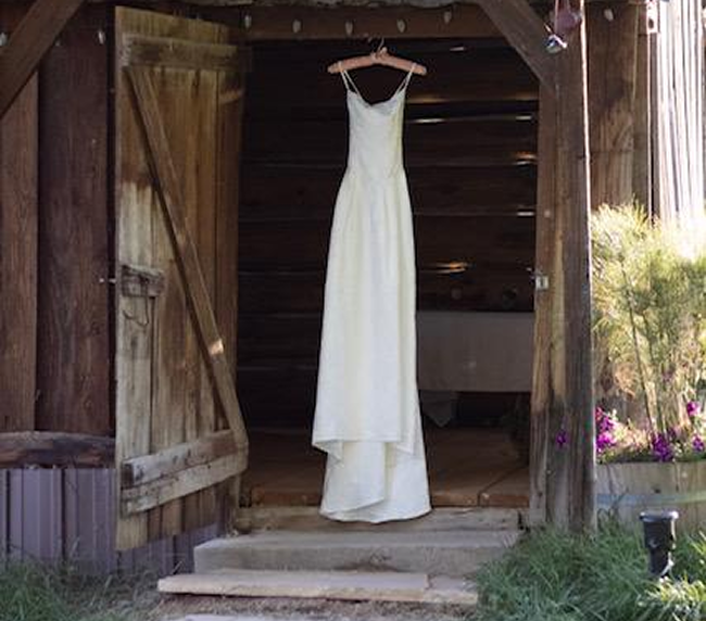 Wedding dress hanging in rustic barn doorway at Three Willows Ranch wedding venue in Bayfield Colorado