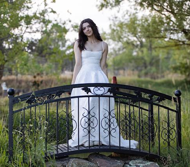 Bride standing on decorative garden bridge at Three Willows Ranch outdoor wedding venue in Bayfield Colorado