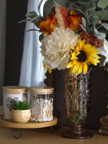 Bridal suite styling table with sunflower bouquet, decorative jars, and elegant mirror accents in a cozy preparation setting.