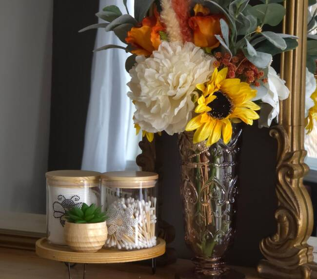 Bridal suite styling table with sunflower bouquet, decorative jars, and elegant mirror accents in a cozy preparation setting.