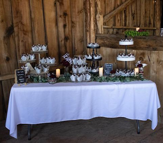 Rustic wedding dessert table setup inside barn at Three Willows Ranch in Bayfield Colorado
