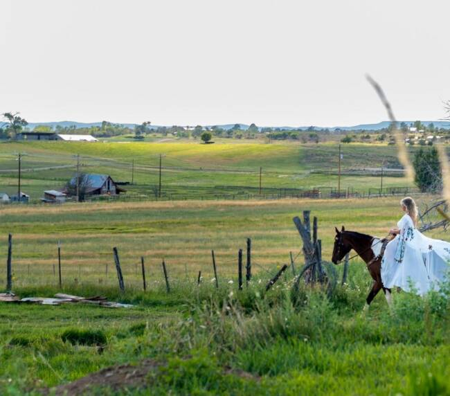 Bride riding horse across open ranch landscape at Three Willows Ranch wedding venue in Bayfield Colorado