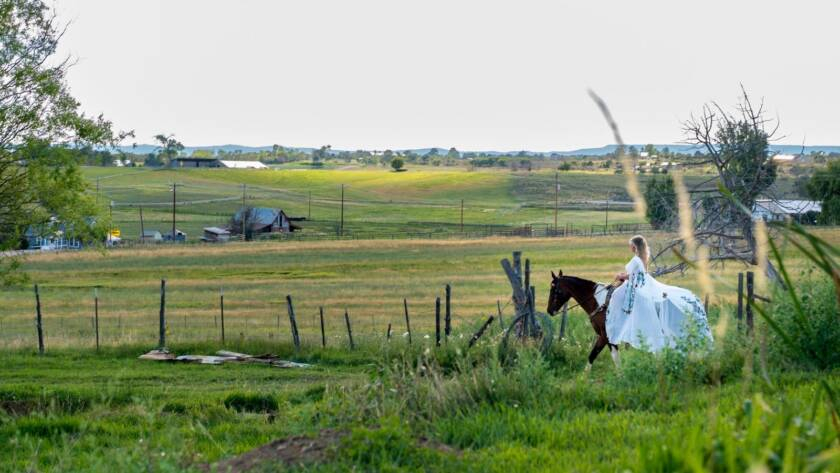 Bride riding horse across open ranch landscape at Three Willows Ranch wedding venue in Bayfield Colorado