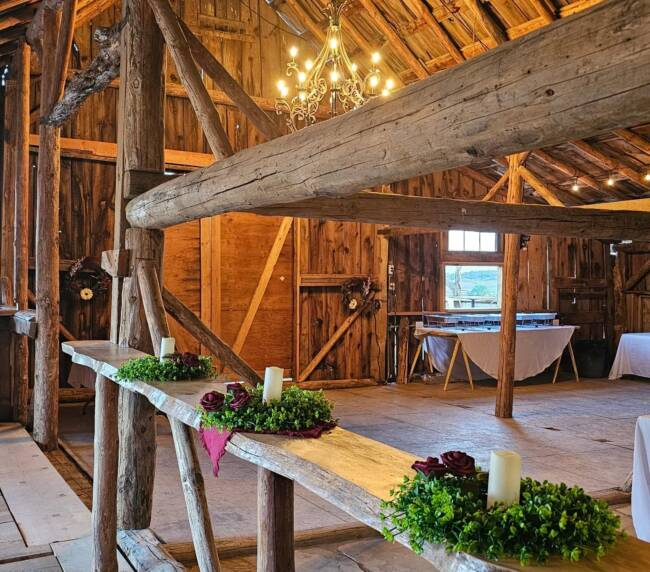 Rustic wooden barn interior with chandelier lighting and elegant wedding décor at countryside ranch venue.