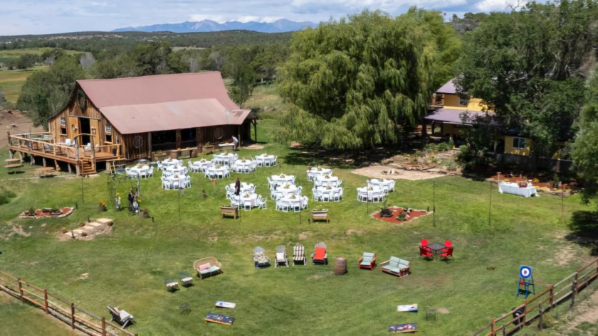 Aerial view of Three Willows Ranch rustic barn with outdoor event lawn, seating area, and mountain views in Bayfield Colorado