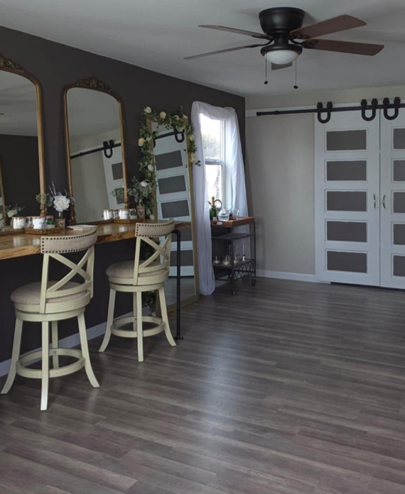 Spacious bridal suite at Three Willows Ranch featuring vanity mirrors, wooden styling counters, barstools, and rustic modern décor.