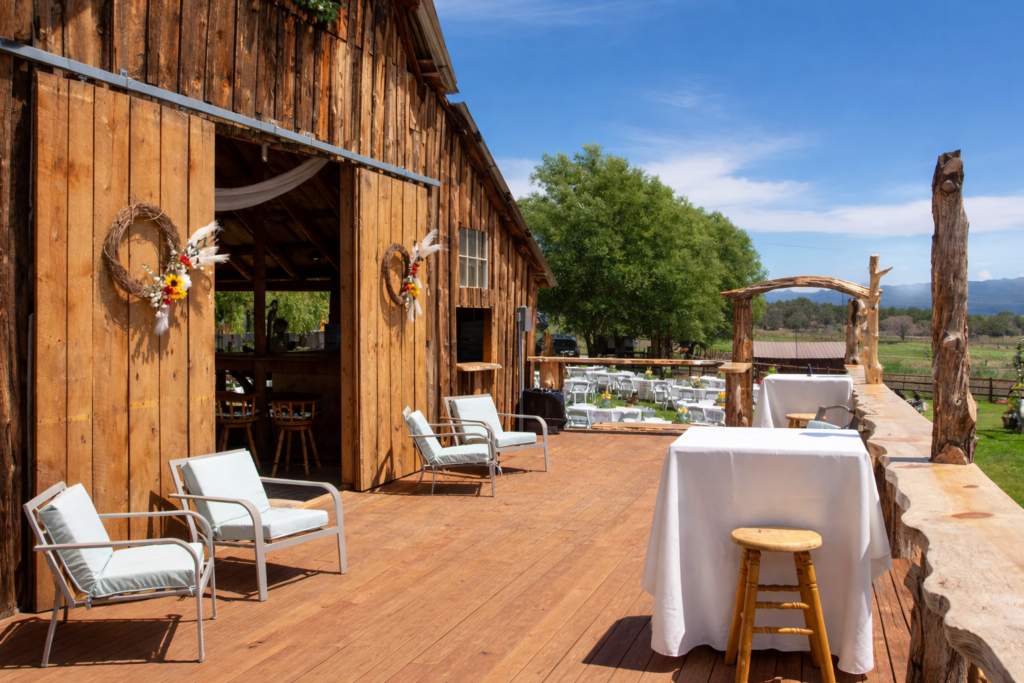 Rustic wooden barn deck at a Colorado ranch with outdoor seating, cocktail tables, and scenic countryside views for private gatherings