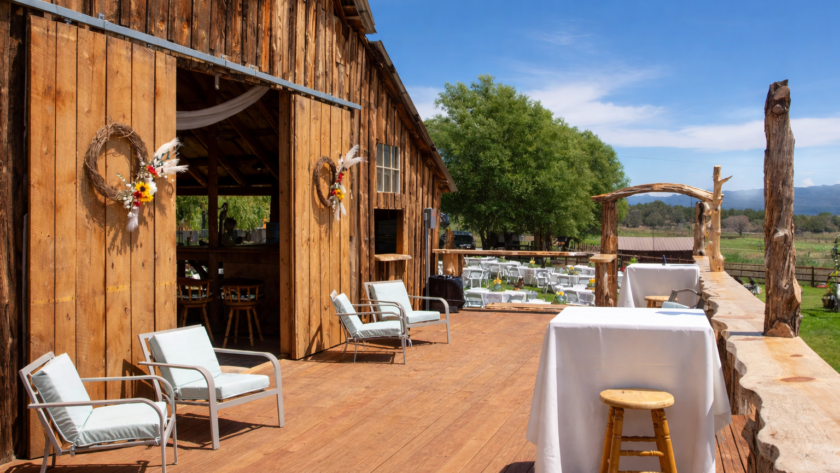 Rustic wooden barn deck at a Colorado ranch with outdoor seating, cocktail tables, and scenic countryside views for private gatherings