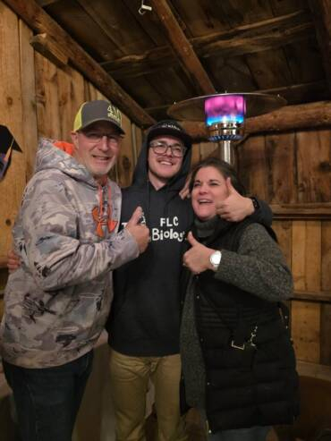 Family celebrating a graduation inside a rustic barn in Bayfield Colorado, sharing joyful moments during a ranch gathering.