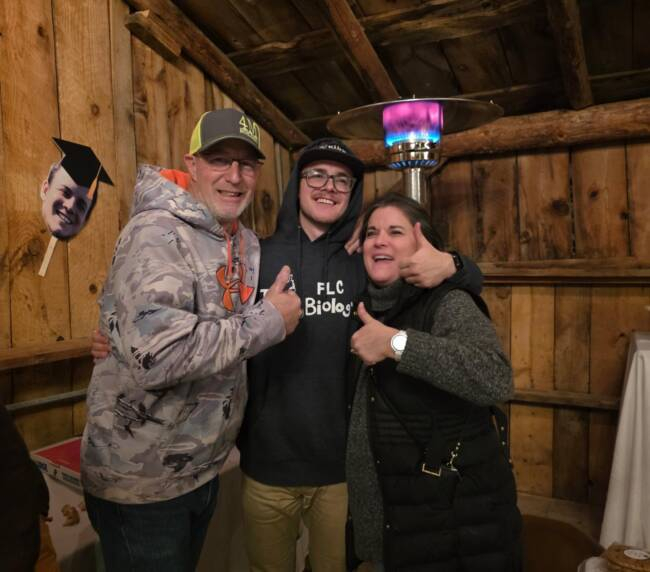 Family celebrating a graduation inside a rustic barn in Bayfield Colorado, sharing joyful moments during a ranch gathering.