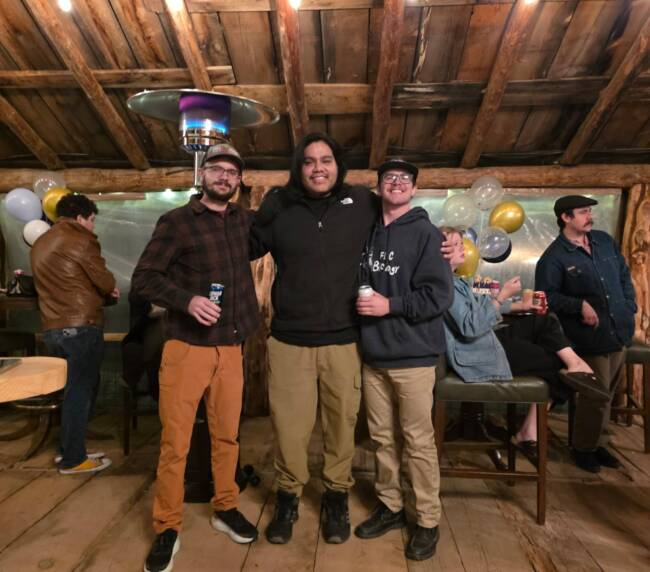 Friends posing together at a graduation party inside a rustic barn venue in Bayfield Colorado, enjoying a warm and festive atmosphere.