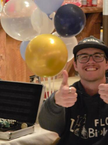 Guest giving thumbs up at a lively indoor barn celebration with balloons and party decorations.