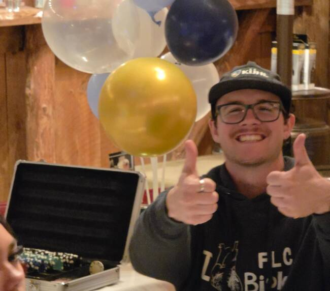 Guest giving thumbs up at a lively indoor barn celebration with balloons and party decorations.