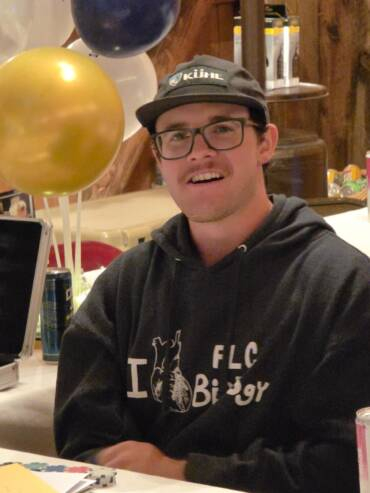 Guest sitting at a decorated table with balloons during a cozy indoor celebration inside a rustic barn venue.