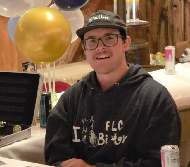 Guest sitting at a decorated table with balloons during a cozy indoor celebration inside a rustic barn venue.