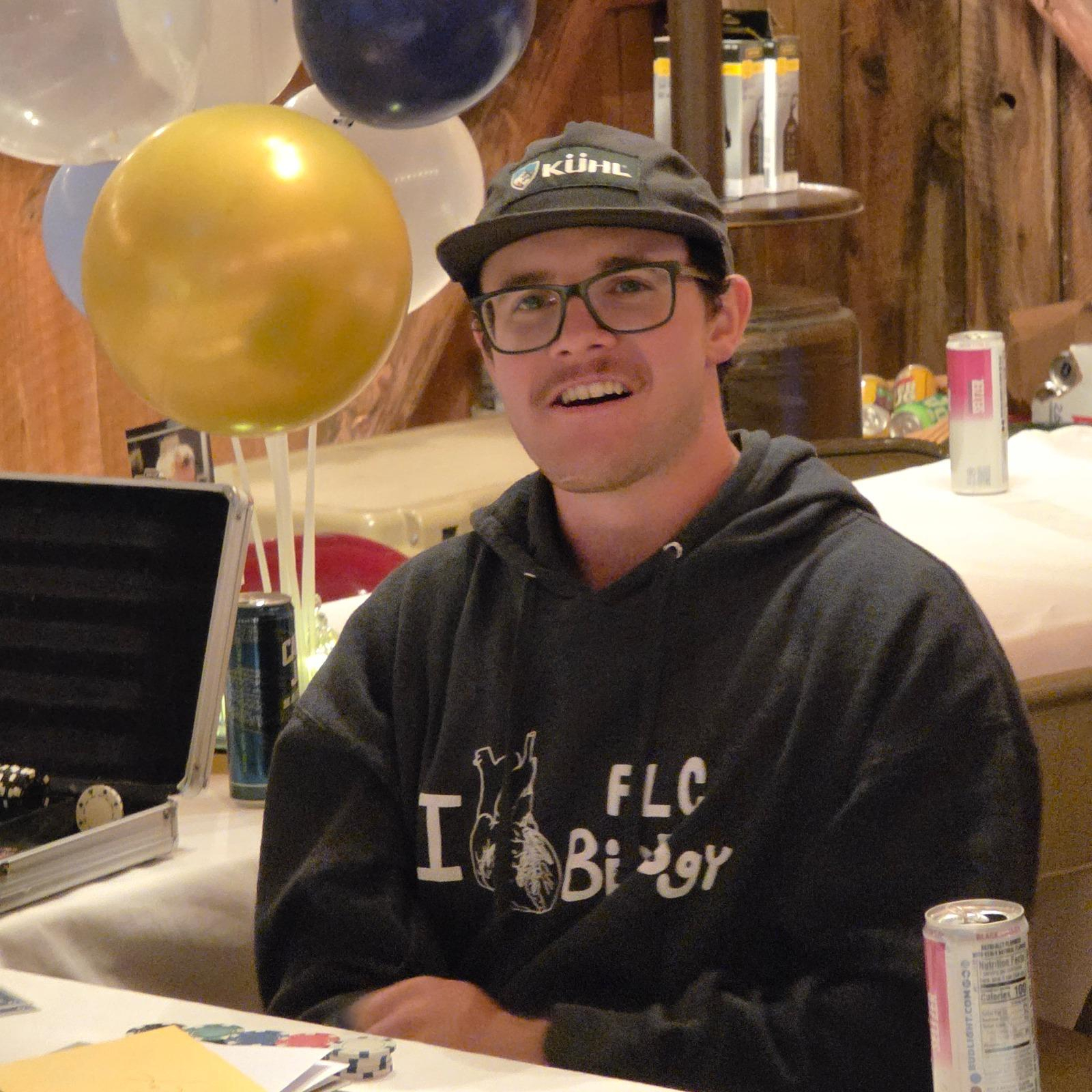 Guest sitting at a decorated table with balloons during a cozy indoor celebration inside a rustic barn venue.