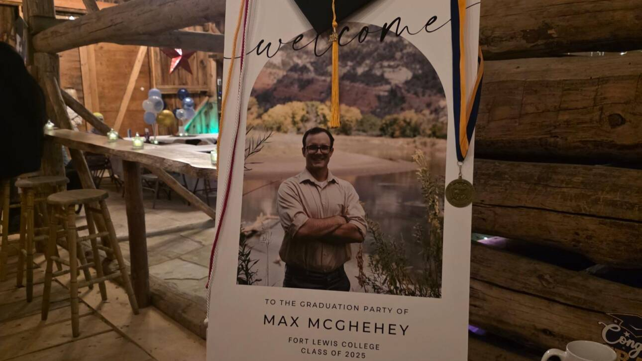 Graduation welcome sign display inside a rustic barn at a Bayfield Colorado ranch venue, decorated with cap and medal for a celebration.