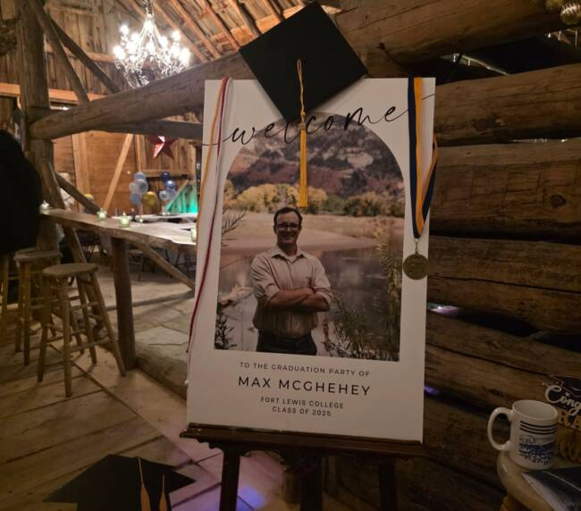 Graduation welcome sign display inside a rustic barn at a Bayfield Colorado ranch venue, decorated with cap and medal for a celebration.