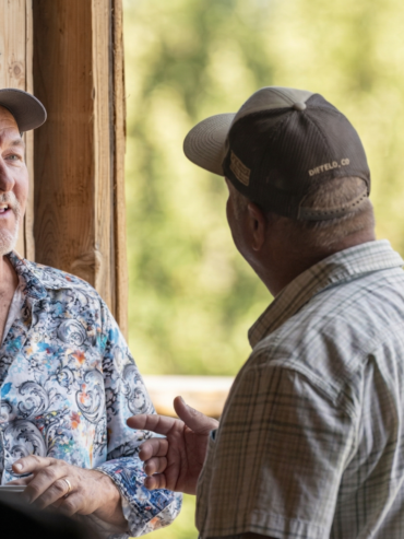 Guests chatting and enjoying conversation inside a rustic barn setting at a Colorado ranch gathering.
