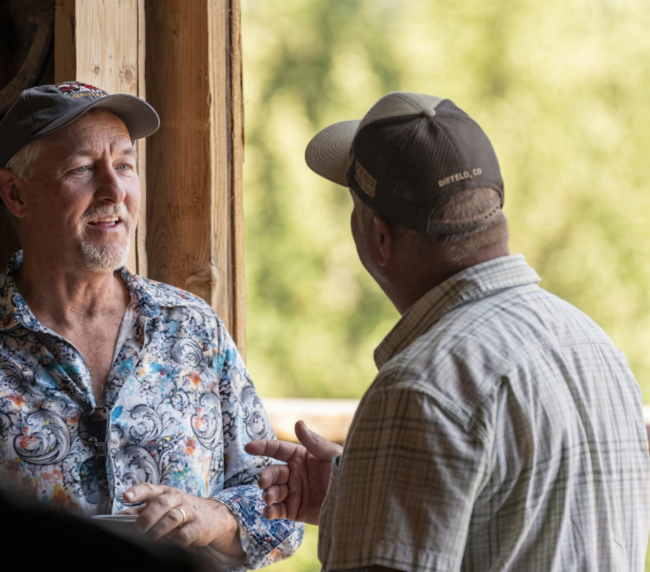 Guests chatting and enjoying conversation inside a rustic barn setting at a Colorado ranch gathering.