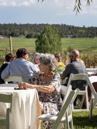 Guests seated at an outdoor ranch reception with scenic mountain and countryside views in Colorado, enjoying a relaxed and elegant gathering.