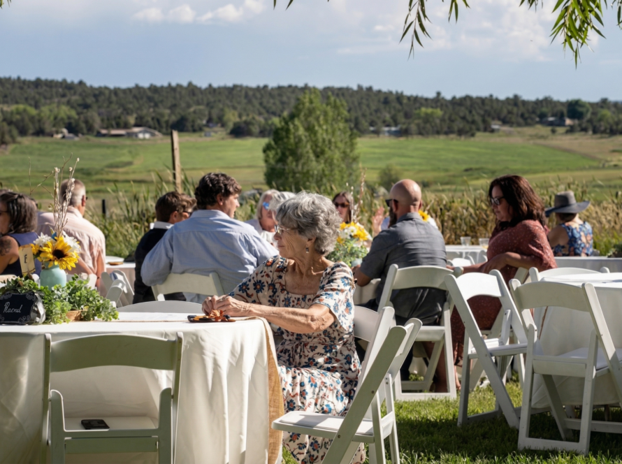 Guests seated at an outdoor ranch reception with scenic mountain and countryside views in Colorado, enjoying a relaxed and elegant gathering.