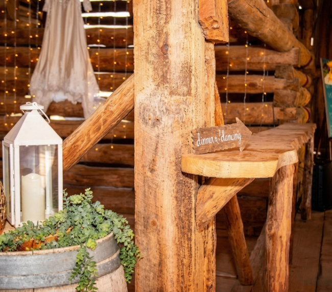Rustic wedding decor with lantern, greenery, and wooden details inside the historic barn at Three Willows Ranch.