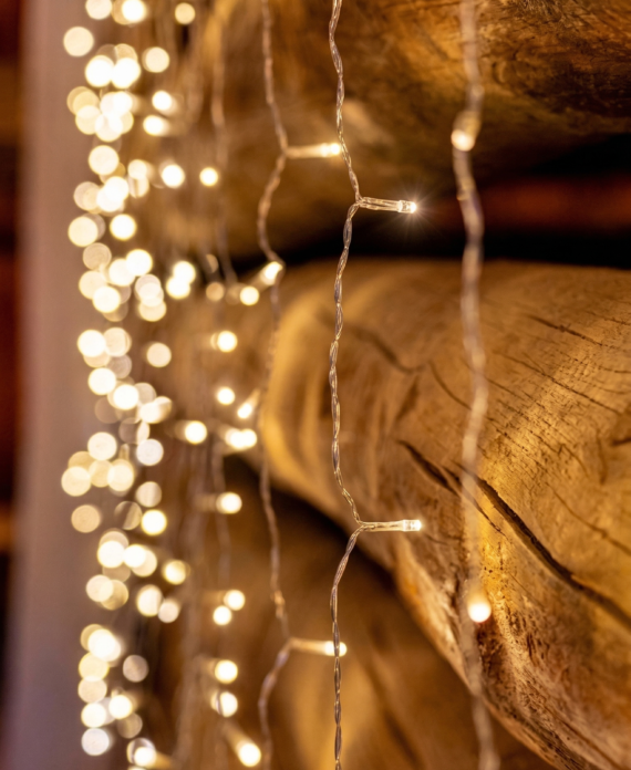 Warm string lights hanging along a rustic log wall creating a cozy atmosphere inside the barn at Three Willows Ranch.