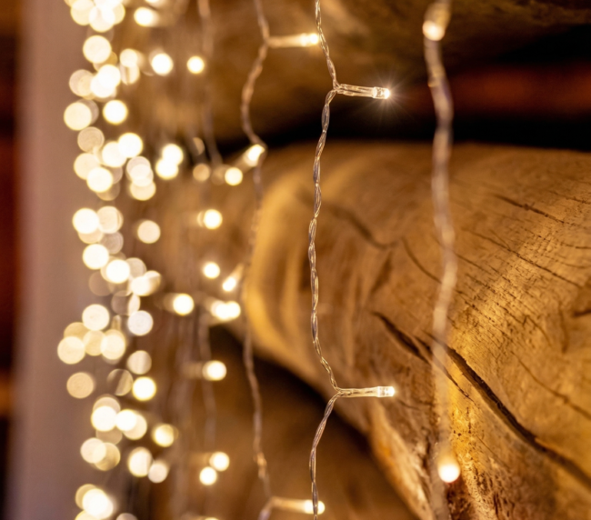 Warm string lights hanging along a rustic log wall creating a cozy atmosphere inside the barn at Three Willows Ranch.
