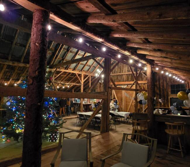 Rustic barn interior with wooden beams, bar area, and warm string lighting at Three Willows Ranch