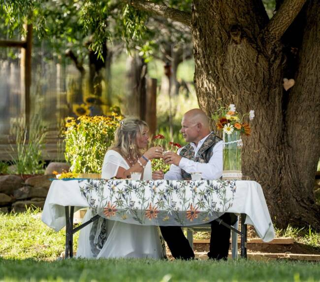 Couple enjoying a romantic outdoor dinner under a tree at Three Willows Ranch rustic wedding venue Colorado