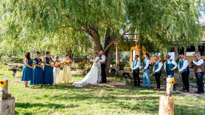 Bride and groom exchanging vows under a willow tree during an outdoor ranch wedding ceremony.