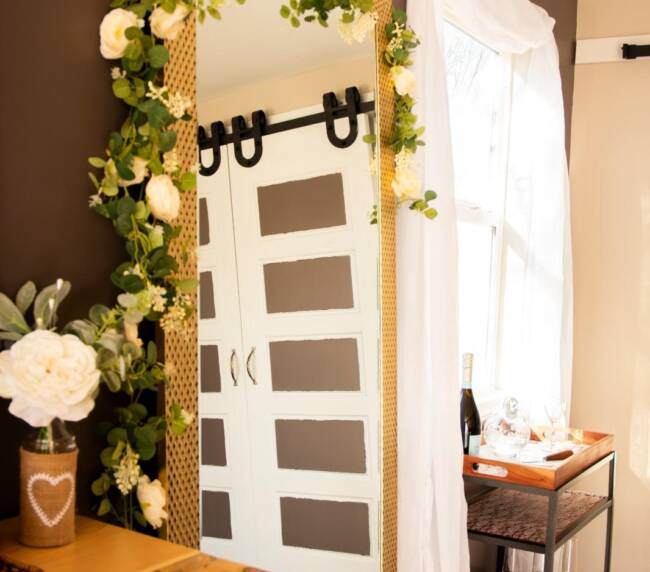 Floral decorated mirror with greenery and white roses in bridal suite at rustic ranch wedding venue