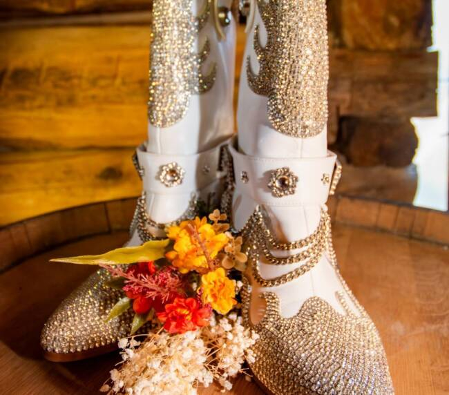 Rhinestone western bridal boots with floral accents on wooden surface in rustic barn setting