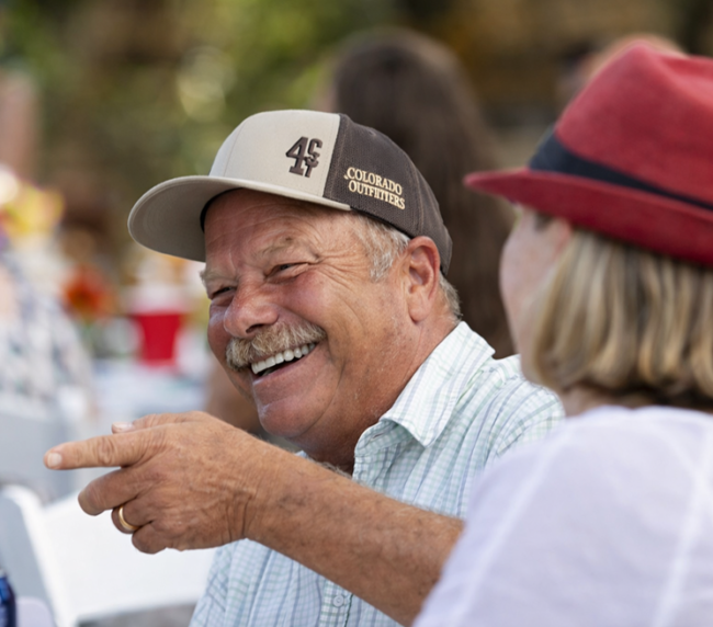 Smiling guests enjoying a lively conversation at an outdoor ranch event, capturing a warm and joyful gathering atmosphere.