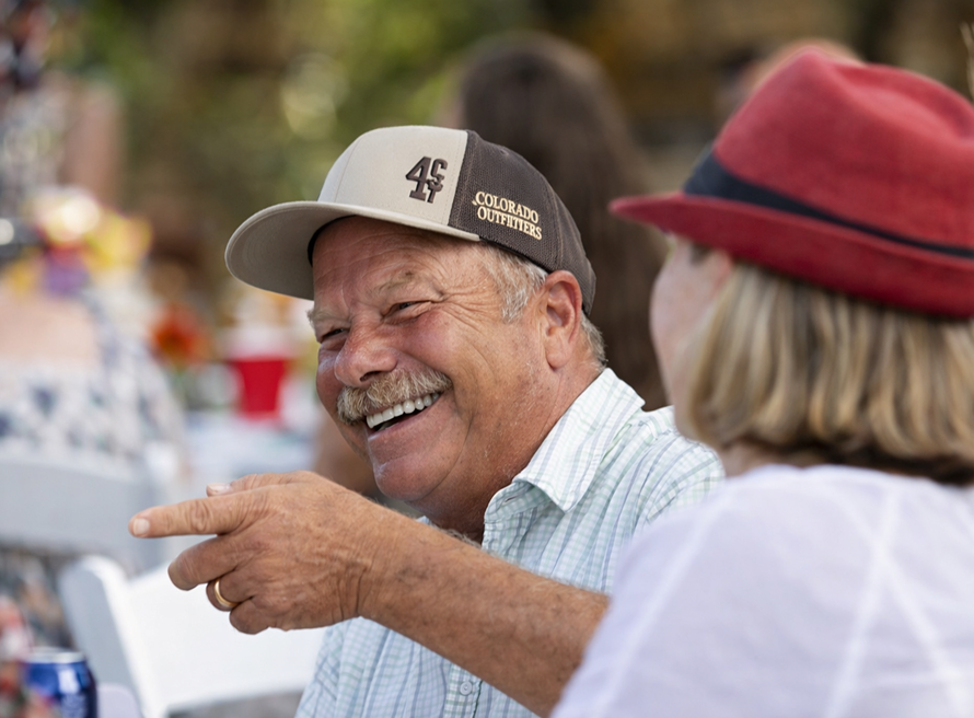 Smiling guests enjoying a lively conversation at an outdoor ranch event, capturing a warm and joyful gathering atmosphere.