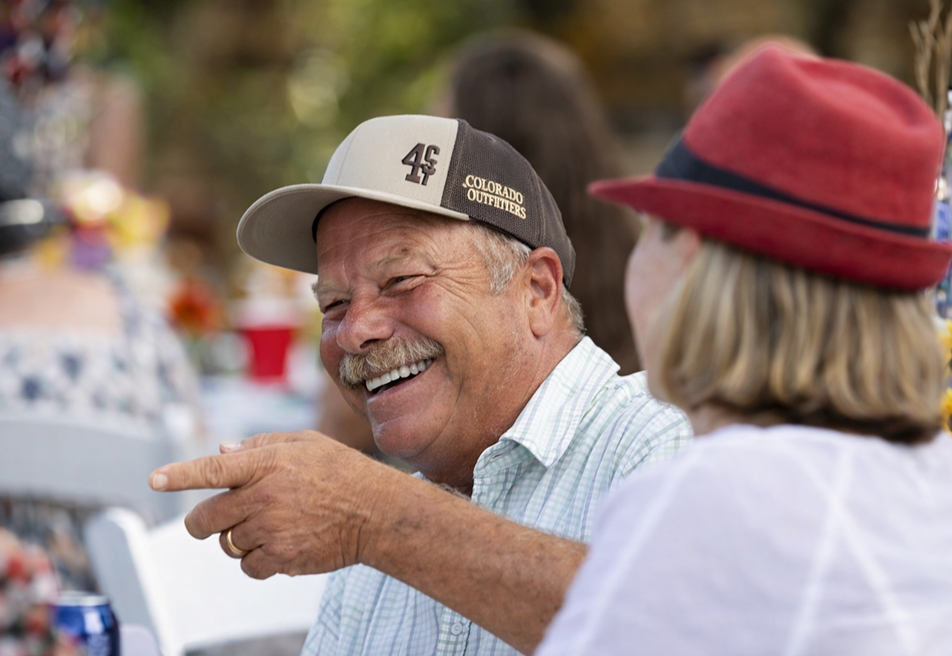 Smiling guests enjoying a lively conversation at an outdoor ranch event, capturing a warm and joyful gathering atmosphere.