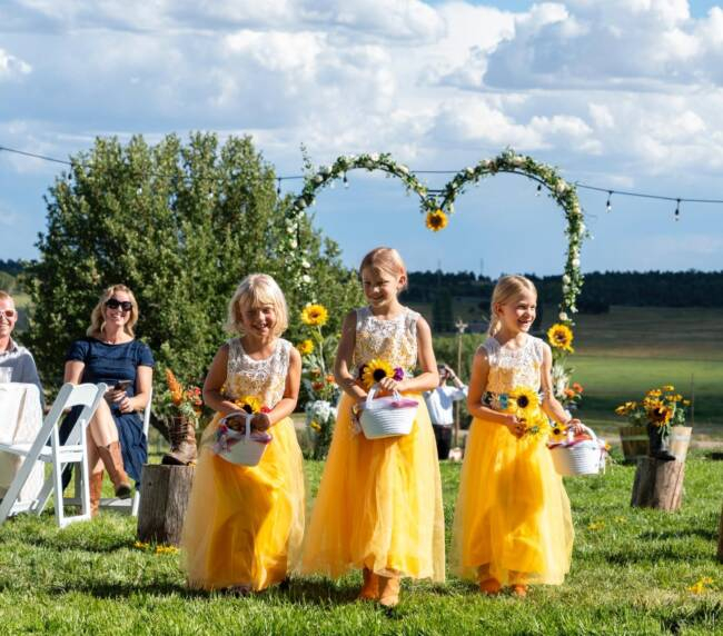 Flower girls walking down the aisle during an outdoor wedding ceremony at Three Willows Ranch Colorado