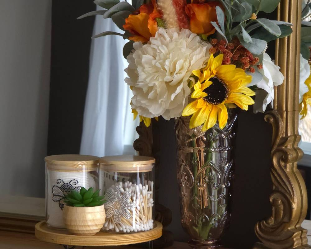 Bridal suite styling table with sunflower bouquet, decorative jars, and elegant mirror accents in a cozy preparation setting.