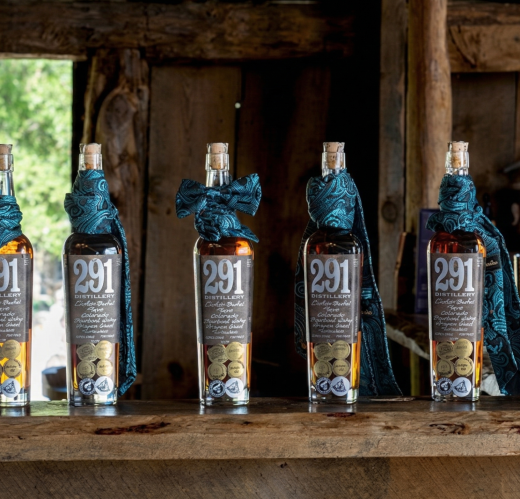 Whiskey bottles lined on a rustic wooden bar inside a historic barn, showcasing a warm and authentic ranch gathering atmosphere in Colorado.
